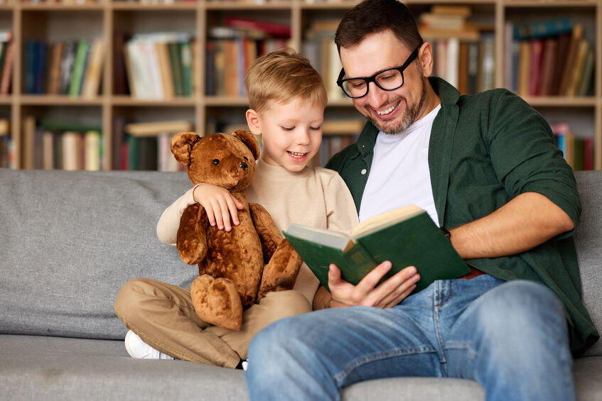 A father reading a book to his toddler son.