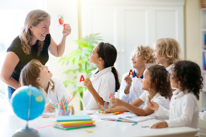 a group of young students learning phonics from a teacher